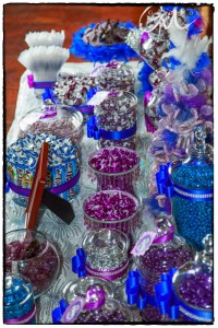 A colorful candy buffet on a table with various sweets in glass jars and bowls, decorated with ribbons and shimmering details, set up by McClelland's Flowers.