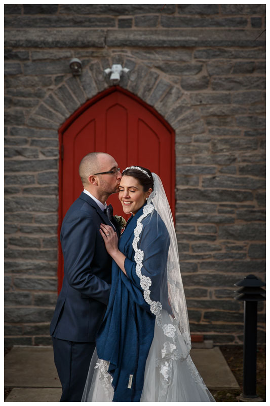 Bride and groom portrait in front of red door across from the Inn on Boltwood