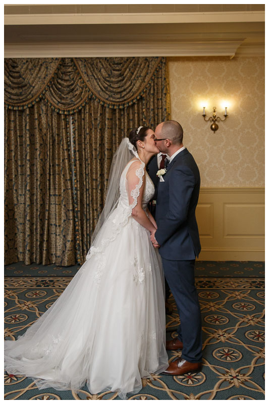 Bride and groom first kiss at the end of wedding ceremony in ballroom at the Inn on Boltwood