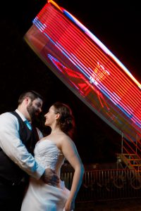 Bride and Groom looking into each others eyes with spinning tilt-a-wheel in background