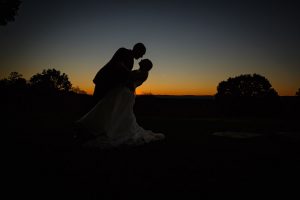 Groom dipping bride at sunset in a silhouette
