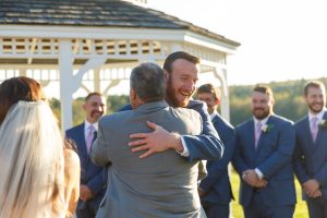 Father of the bride and groom hug at beginning of ceremony