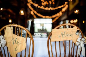 Mr. and Mrs. signs on chairs with twinkle lights in background in reception