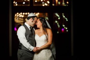 Night time photo with jewish bride and groom with twinkle lights blurred in background