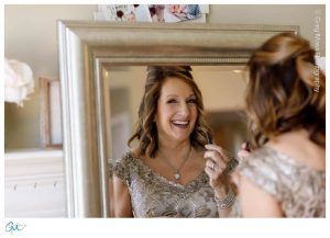 Mother of the bride laughing in the mirror while