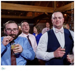 Groom and friend on dance floor with drink and straw