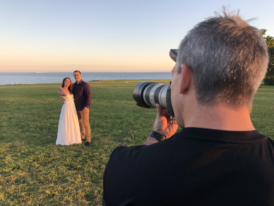 Photographer capturing a couple during their engagement session in Harkness Memorial State Park by the sea at sunset.