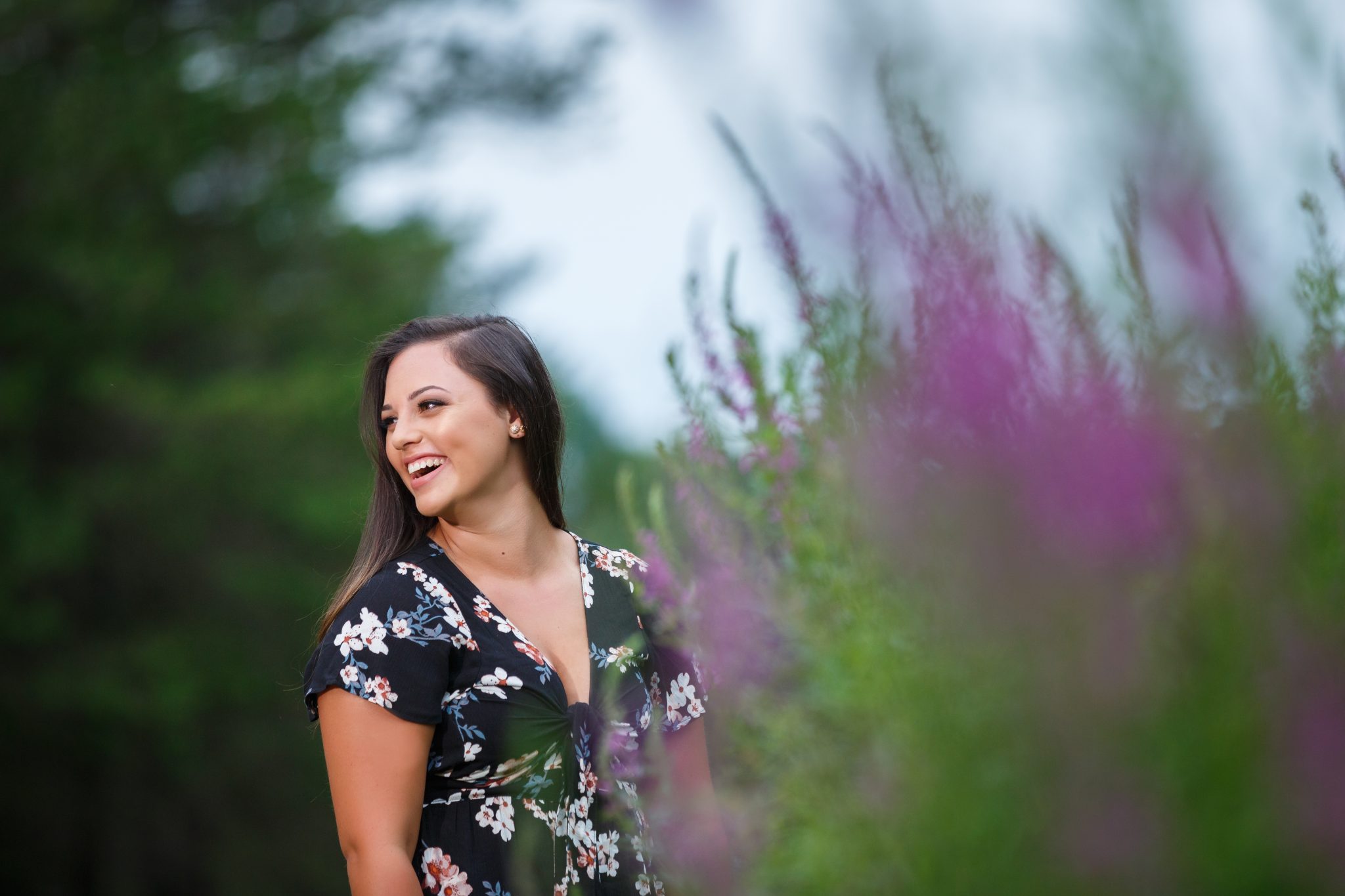 High School Senior Girl laughing with purple flowers in the foreground