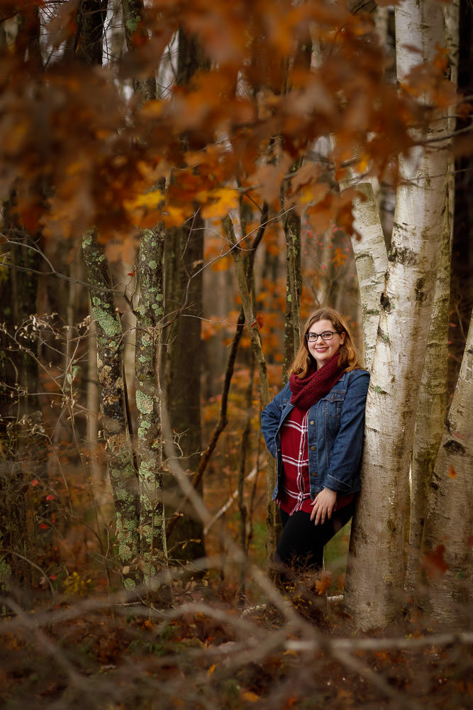 Senior portrait in the fall leaning against a birch tree