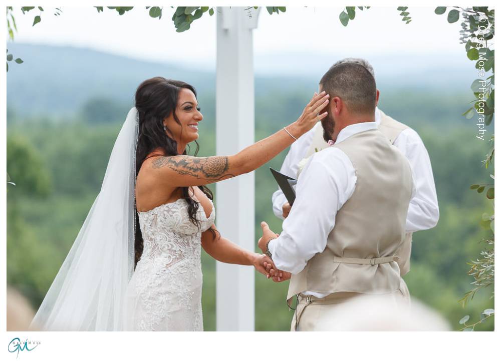 Bride wiping tear from grooms face during ceremony