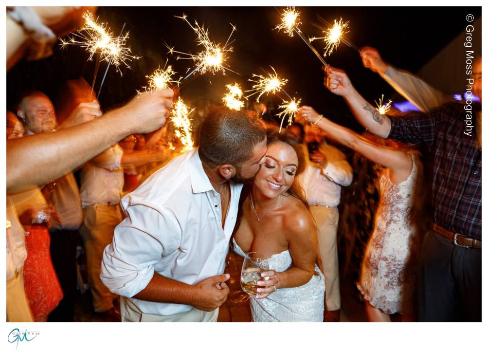 Groom kissing bride surrounding by sparklers during exit from the reception
