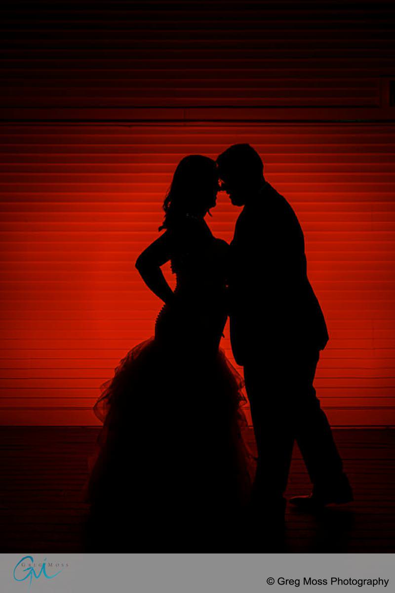 Silhouette of a couple embracing in front of a red barn, creating a romantic atmosphere.