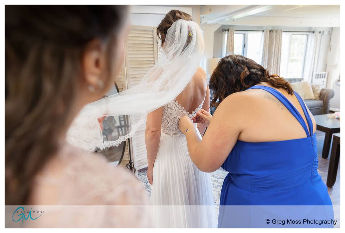 Maid of honor helping bride with wedding dress