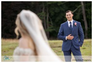Groom smiling at bride in field