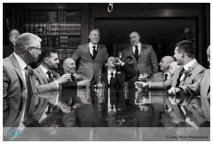 Black and White photo of Groom, Fathers, groomsmen in library at publick house toasting with whiskey