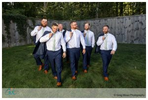 Walking photo of groom and groomsmen with jackets over their shoulders