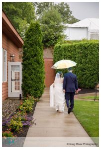 Bride and groom walking with clear umbrella after first look