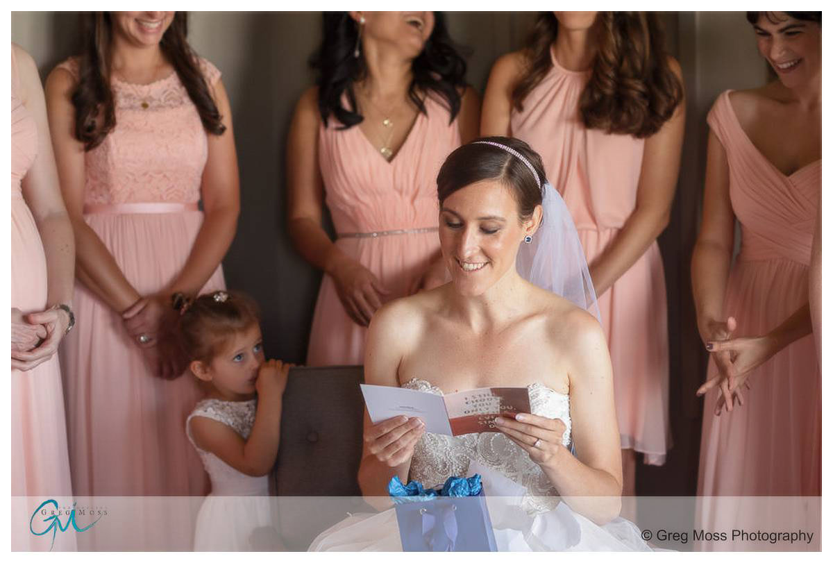 Bride reading letter from groom surrounded by bridesmaids
