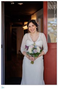 Bride with bouquet in front of door at Red Barn