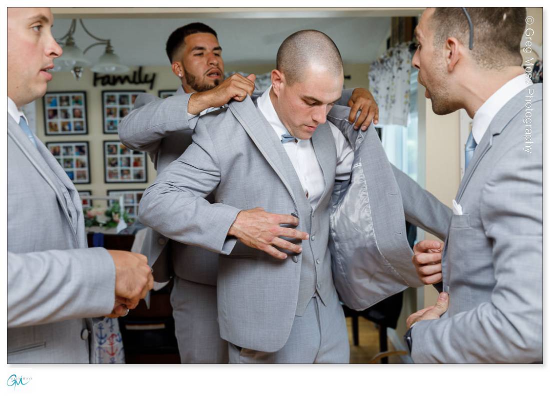 Groomsmen helping groom getting dressed