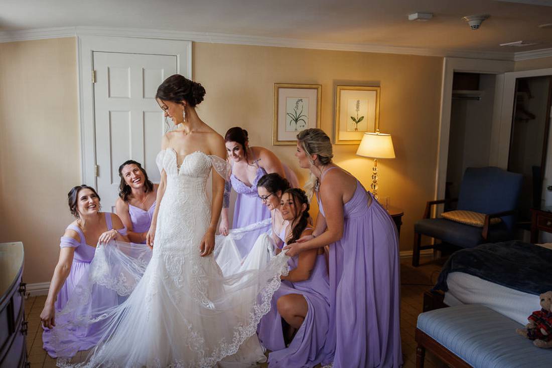 Bridesmaids helping to arrange brides dress