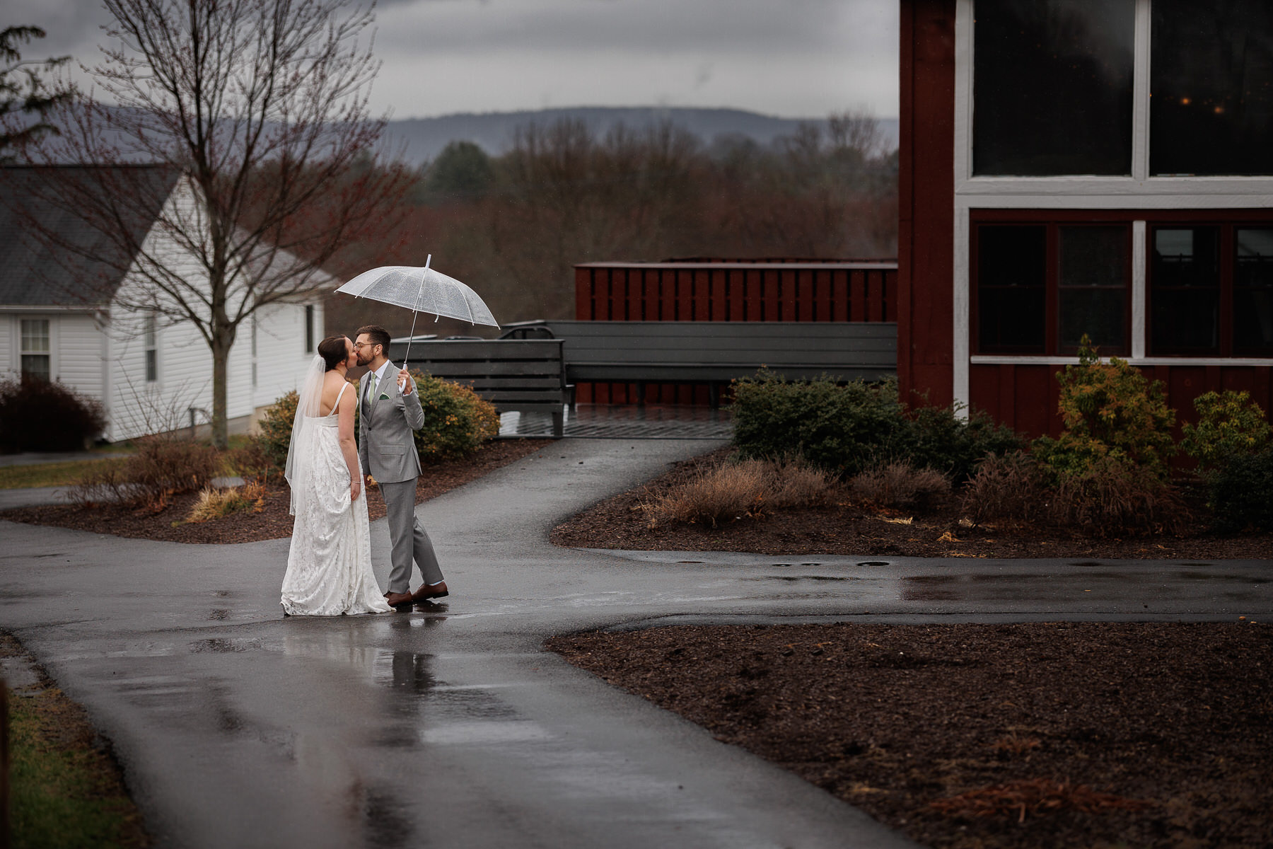 Red Barn photo with wedding couple in the rain with umbrellas
