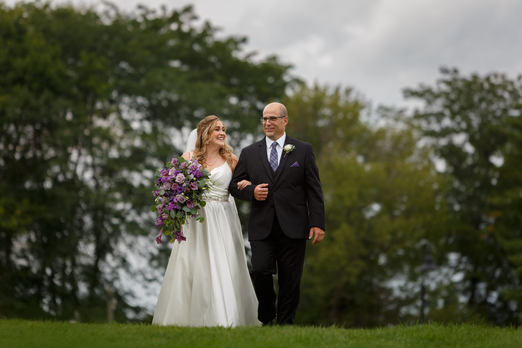 Bride and father walking towards outdoor ceremony at the Red Barn