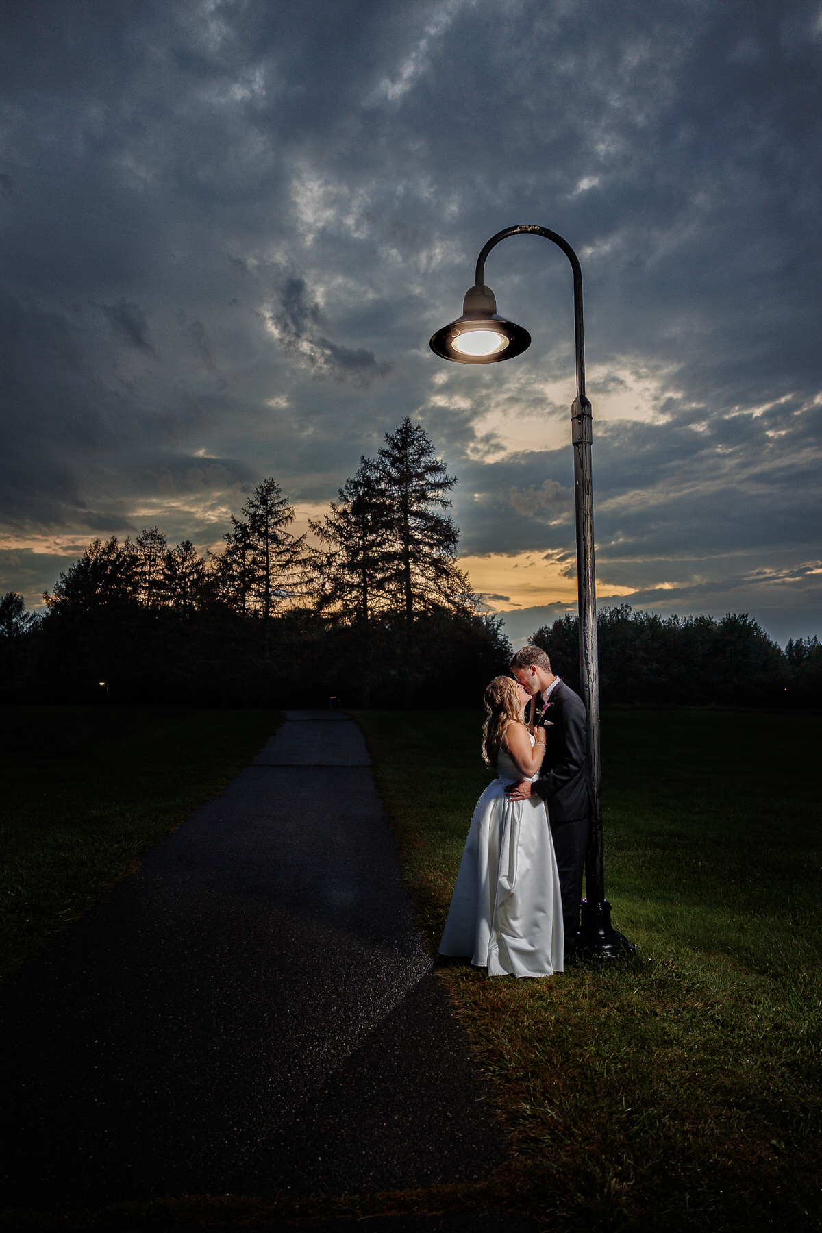 Dramatic photo of bride and groom outside at dusk under lamp post