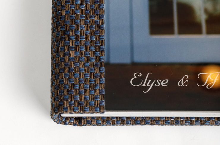 Close-up of a brown woven wedding album cover with "Elyse & TJ" written on it in elegant script.