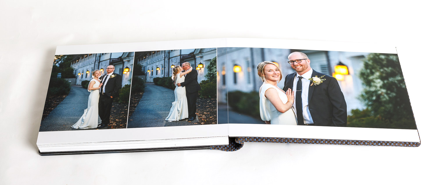 Open wedding album designs displaying two pages with pictures of a bride and groom posing outdoors at dusk.